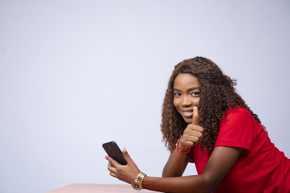 Happy customer giving a thumbs up while holding her phone