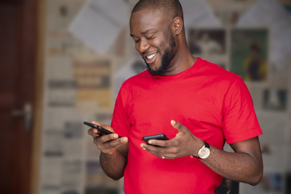Man smiling while using two phones