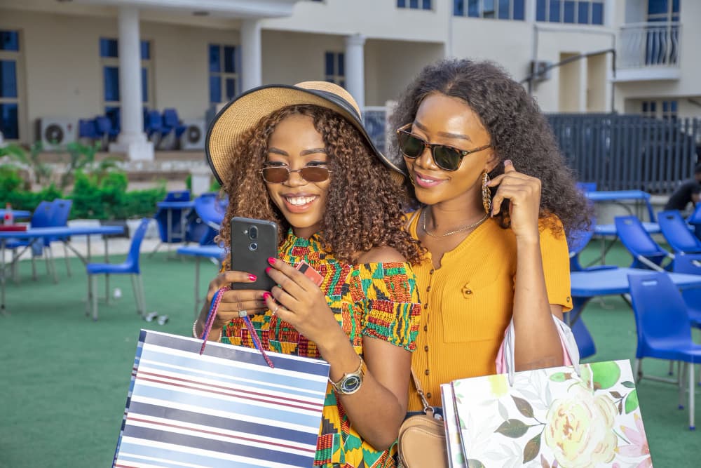 Two friends reading a message together while out shopping